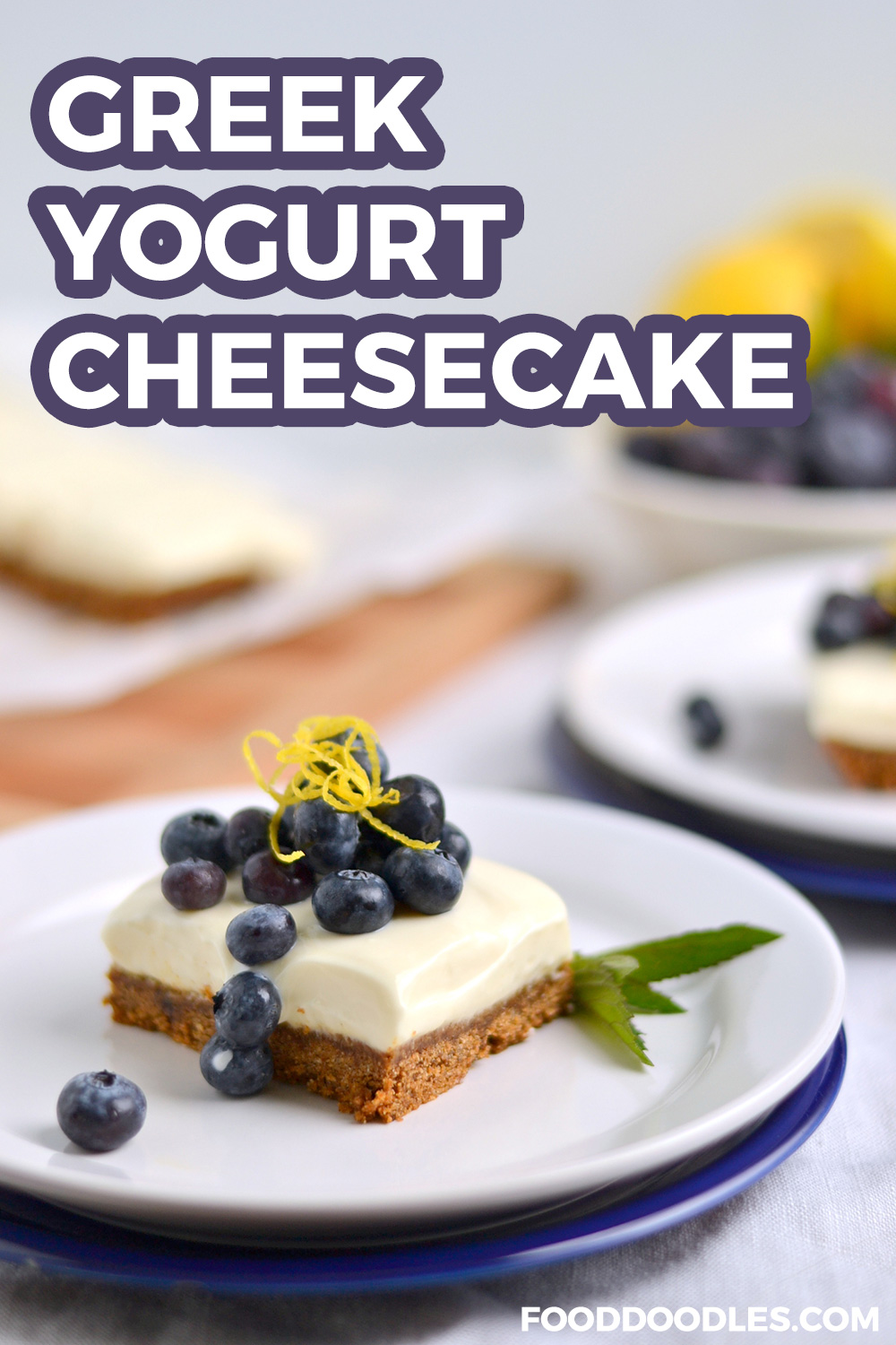 pin image of a slice of greek yogurt cheesecake topped with fresh blueberries and lemon zest