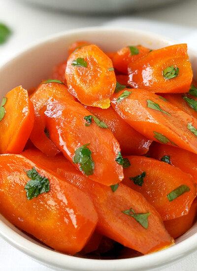 image of a bowl full of bright orange glazed carrots garnished with green parsley