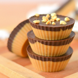 image of stacked dark chocolate peanut butter freezer fudge cups topped with chopped peanuts