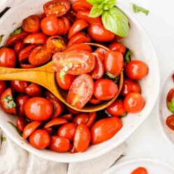 photo showing a spoon over a bowl full of italian tomato salad with juicy fresh tomatoes and fresh basil ready to serve it up