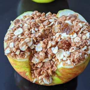 closeup photo showing an air fryer baked apple with an oat-based crumble filling with cinnamon, raisins and pecans