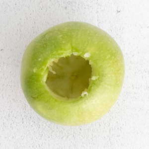 process photo showing a bright green apple that has been cored to make air fryer baked apples