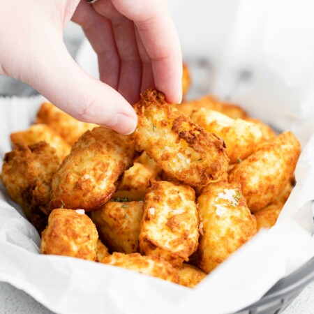 Hand picking up air fryer tater tots
