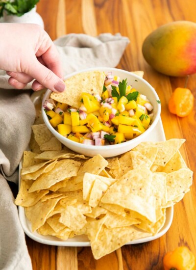 hand dipping chip in mango habanero salsa
