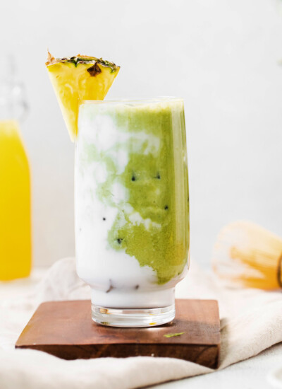 pineapple matcha drink in glass on brown cutting board