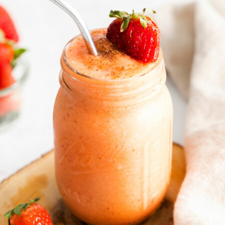 Photo of a jar full of mango strawberry banana smoothie that is thick and creamy with sweet chunks of mangos, strawberries and silky bananas making it naturally vegan, paleo, and whole30-friendly.