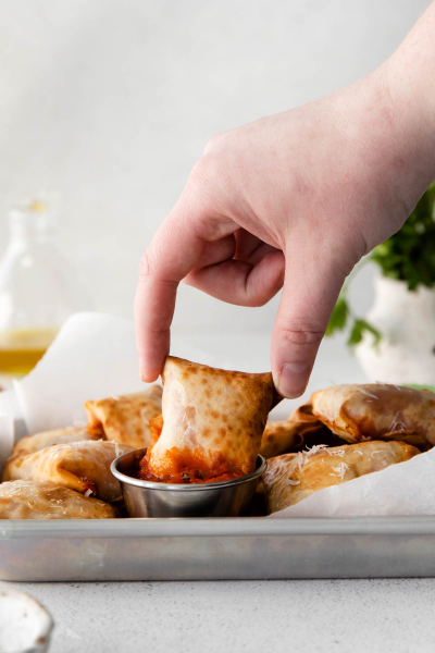 fingers picking up air fryer pizza rolls 