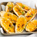 Image showing a plate full of Air Fryer Potato Skins loaded with melted cheddar cheese, crispy bacon and chopped chives.