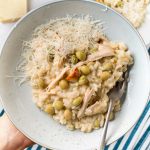 Image of a bowl of creamy chicken and pea risotto garnished with grated parmesan cheese