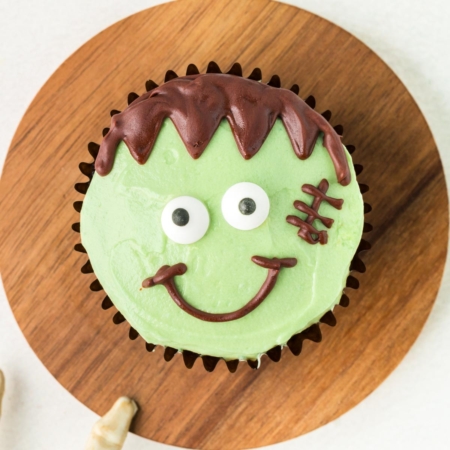 Frankenstein cupcake on a round wooden cutting board