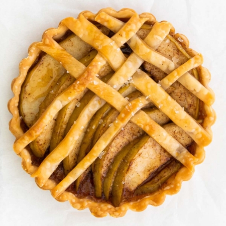 close up top view of a mini apple tart on a white background