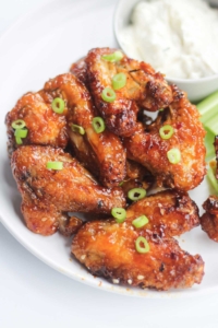 stacked honey garlic chicken wings cooked to perfection, golden brown and garnished with slivers of green onions