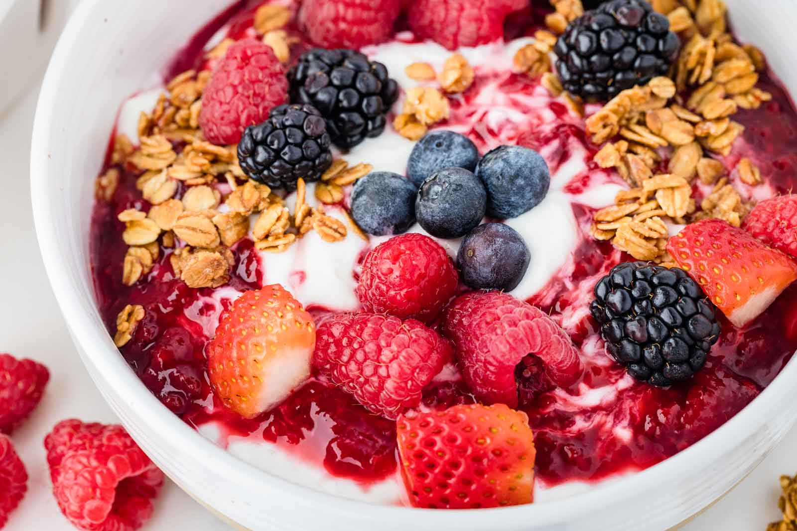 close-up of yogurt bowls with berries and granola on top