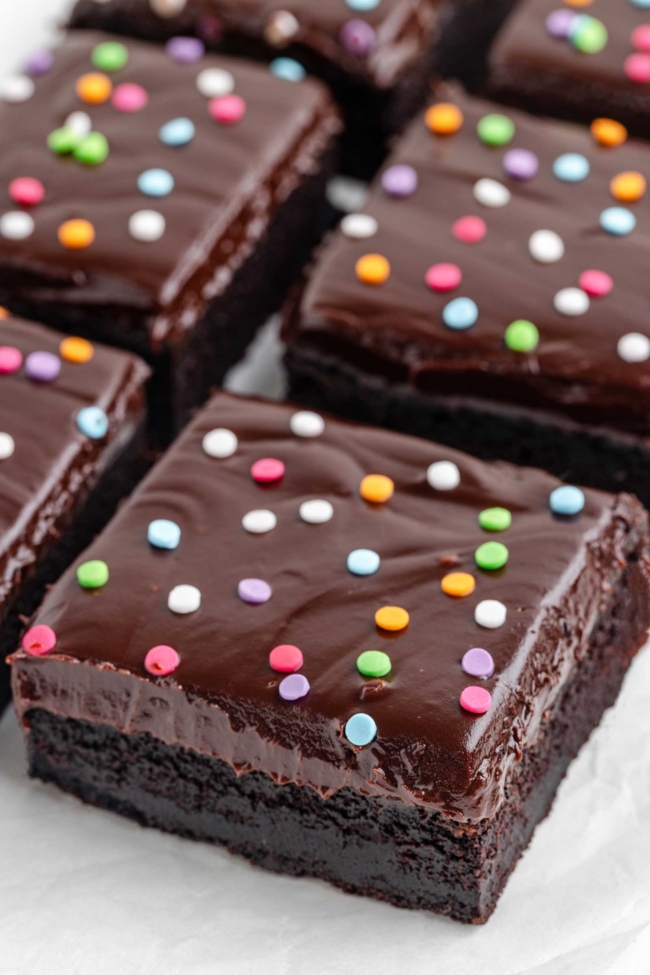close-up to a brownie with ganache and colorful sprinkles on top
