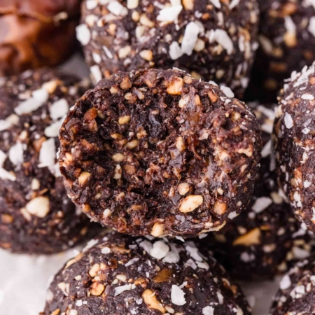 close-up of a stack of chocolate coconut nut balls on a white plate