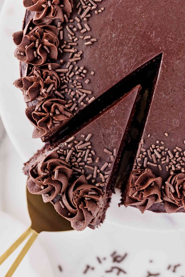slice of cake being taken from the full dark cocoa cake