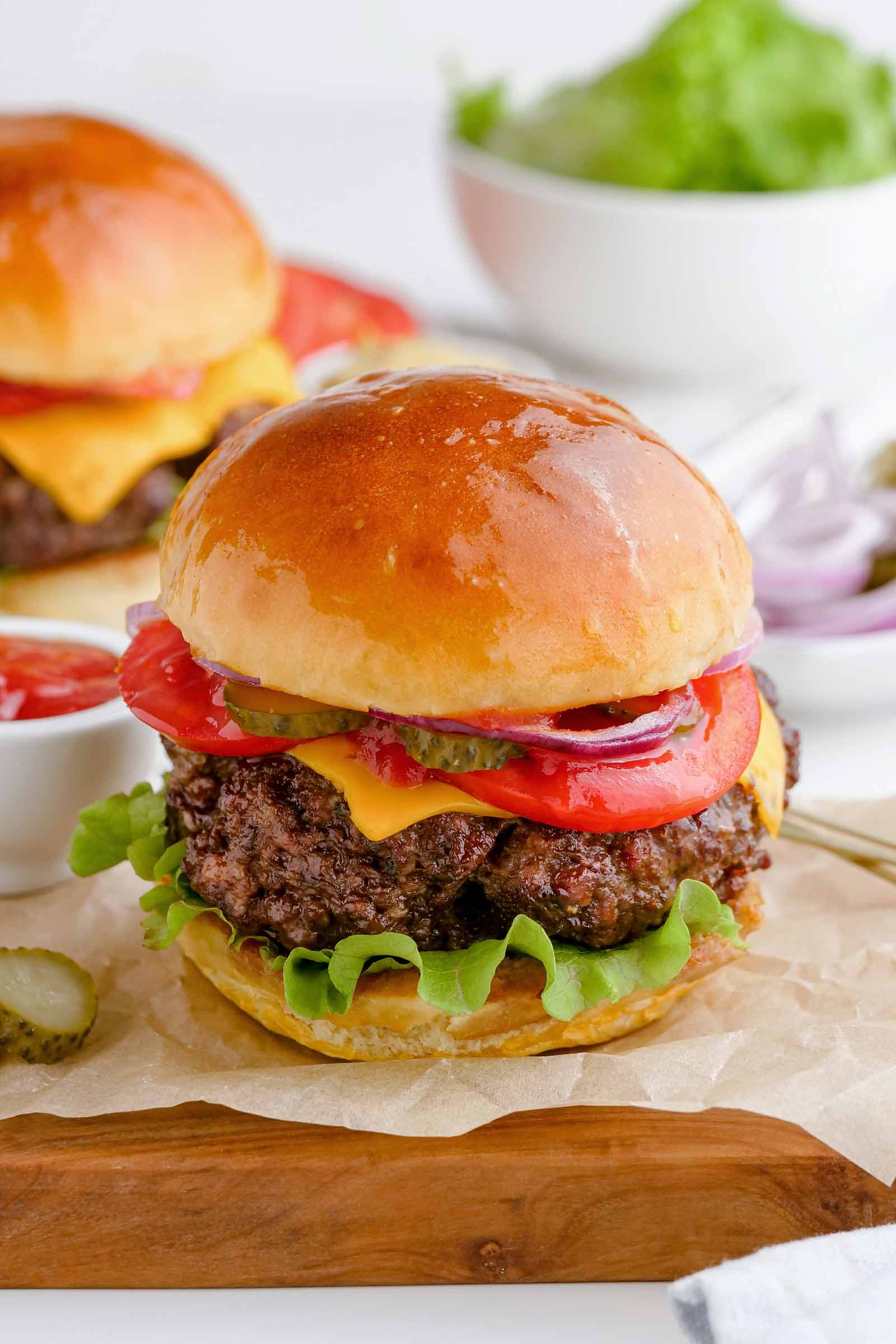 close-up of an air fryer burger on parchment paper with another burger in the background