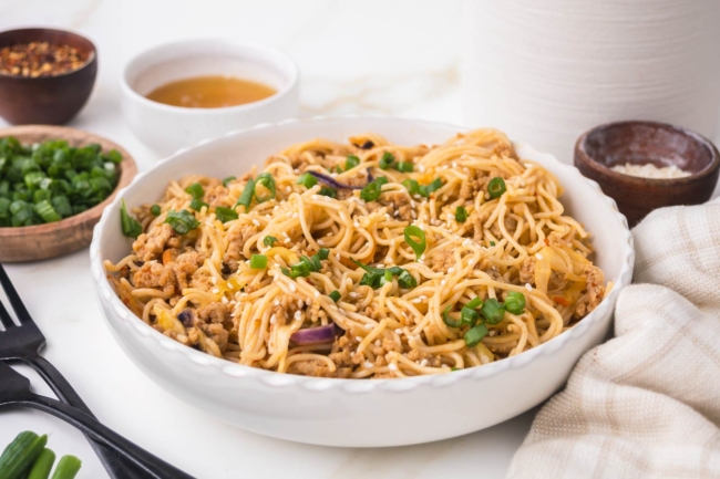 white bowl on white table filled with honey garlic noodles