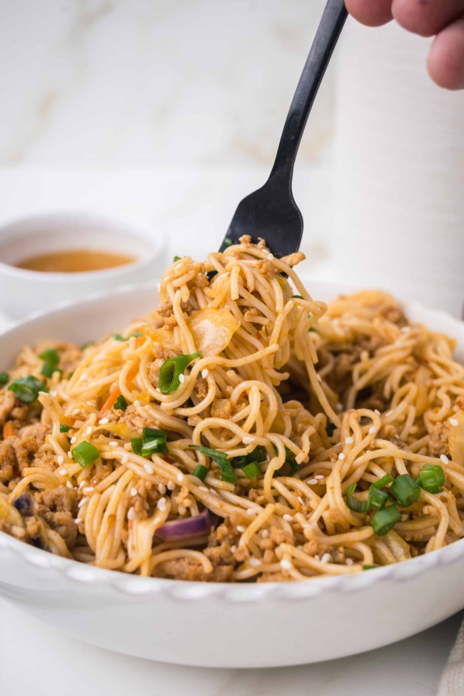 fork picking up some noodles from a bowl of honey garlic noodles