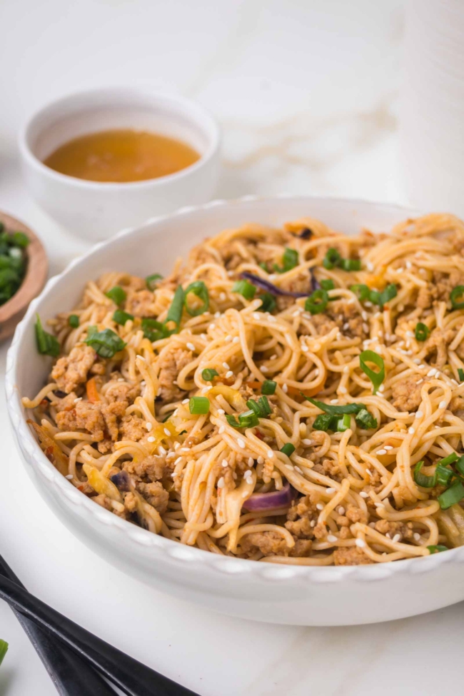 closeup of honey garlic noodles in a white bowl on a white table