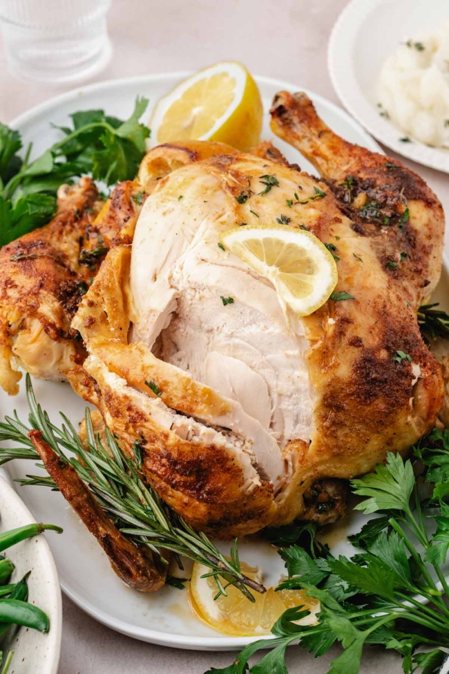 sliced open oven roasted whole chicken on a white serving dish
