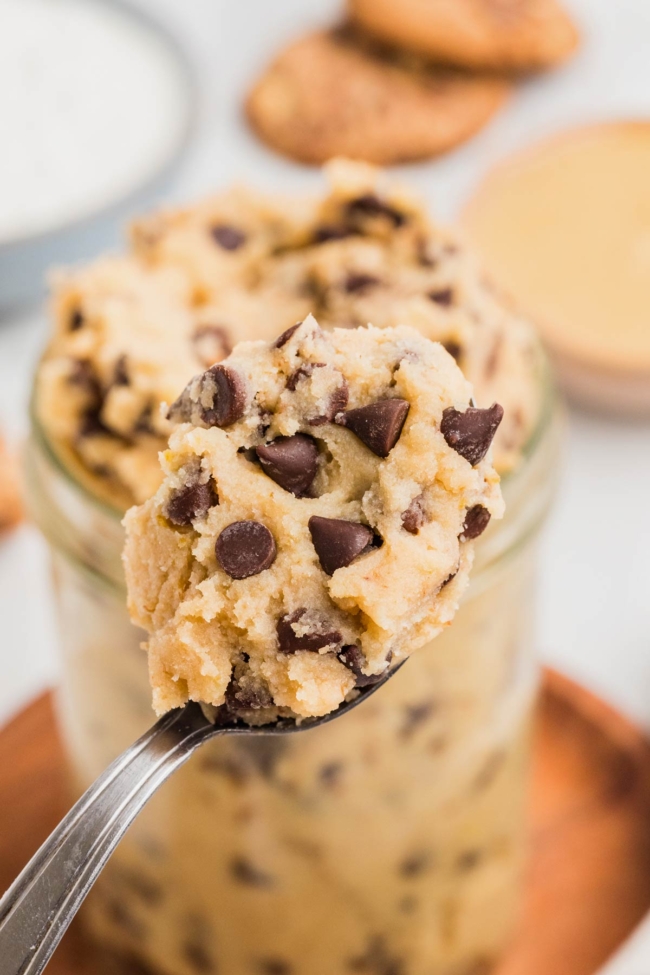 spoon digging into jar with cottage cheese cookie dough on a white table