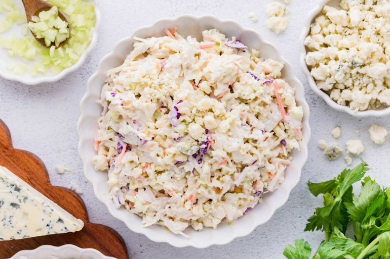overhead shot of blue cheese coleslaw in a white bowl on a white table