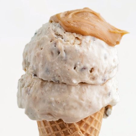 2 scoops of peanut butter cottage cheese ice cream in an ice cream cone with peanut butter on top