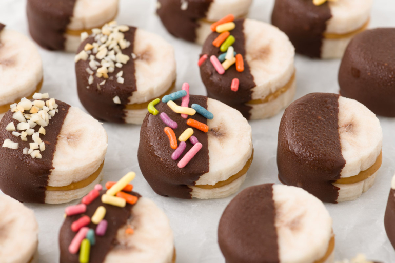 peanut butter bananas with sprinkles and chopped nuts on them