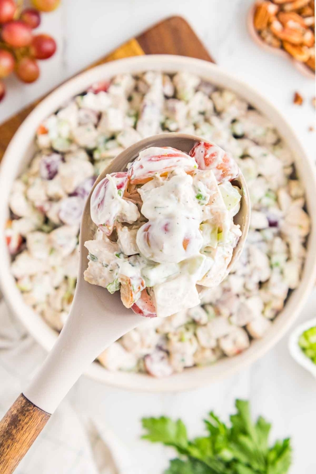 grape chicken salad being removed from white bowl with a white spoon