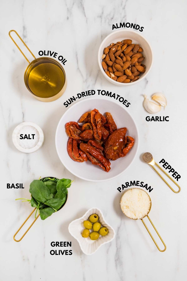 ingredients laid out to make sun-dried tomato pesto on a white table