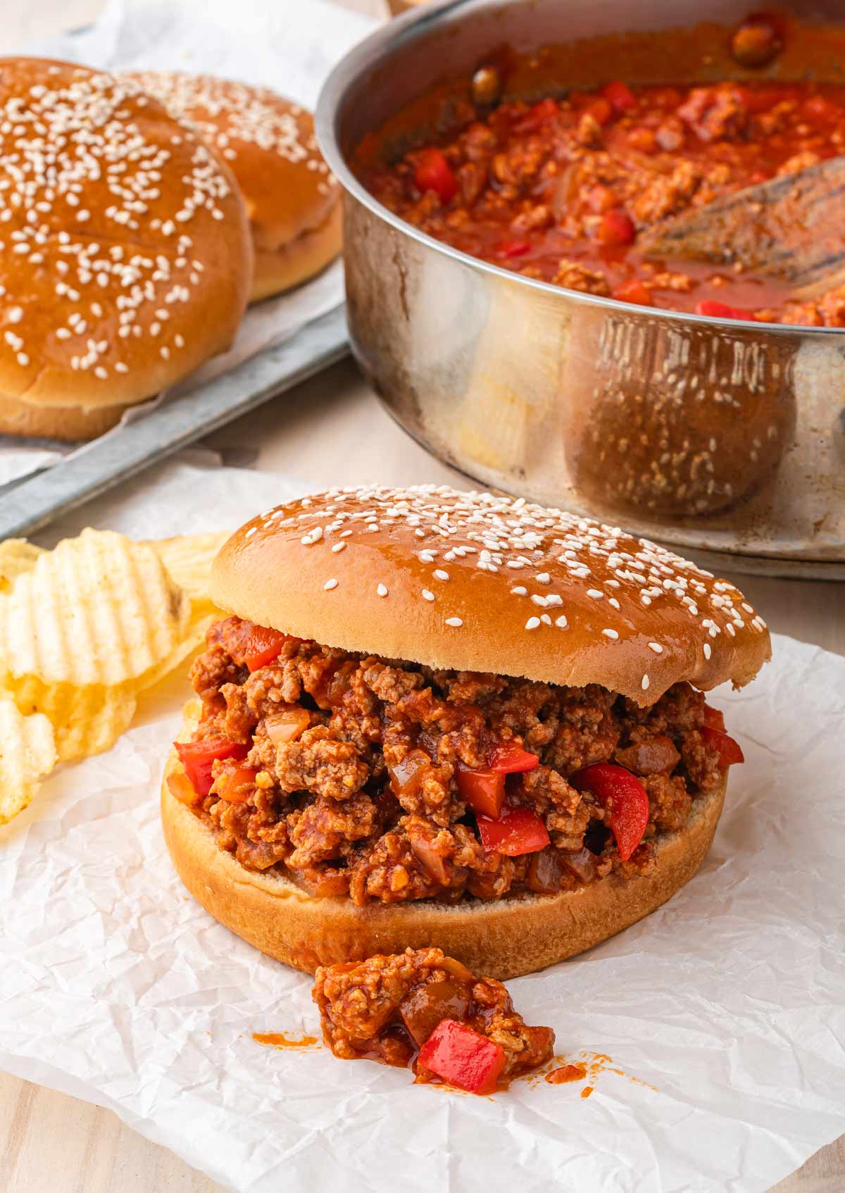two ground turkey sloppy joes on parchment paper with the skillet in the background