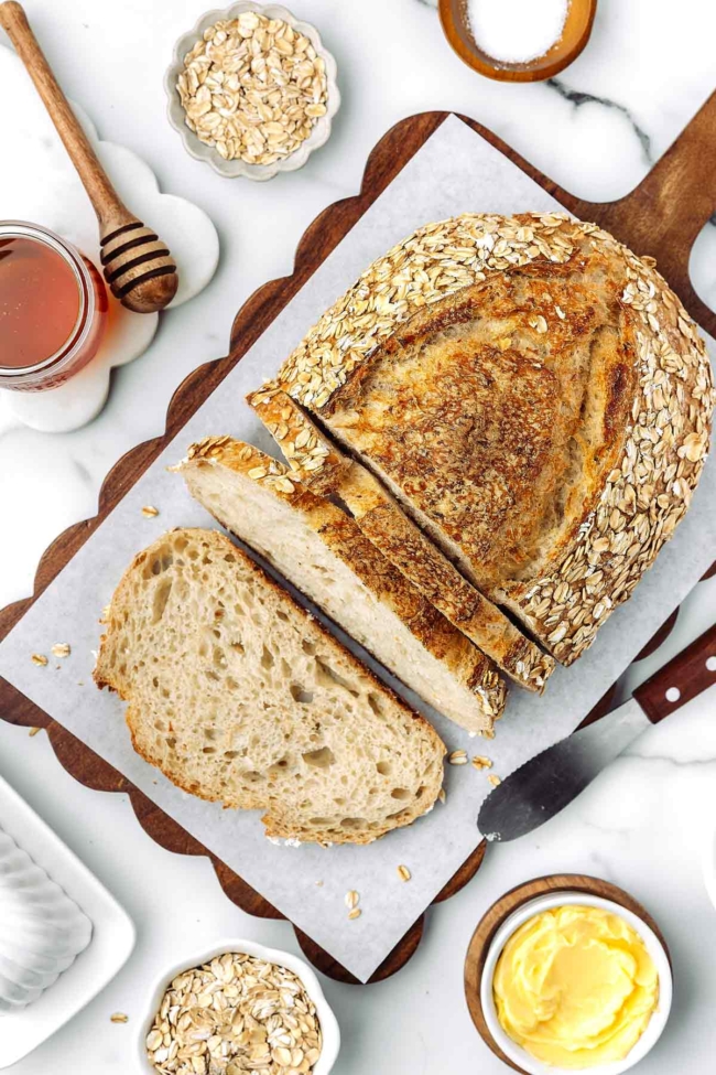 overhead shot of sliced up honey oatmeal sourdough bread on a cutting board