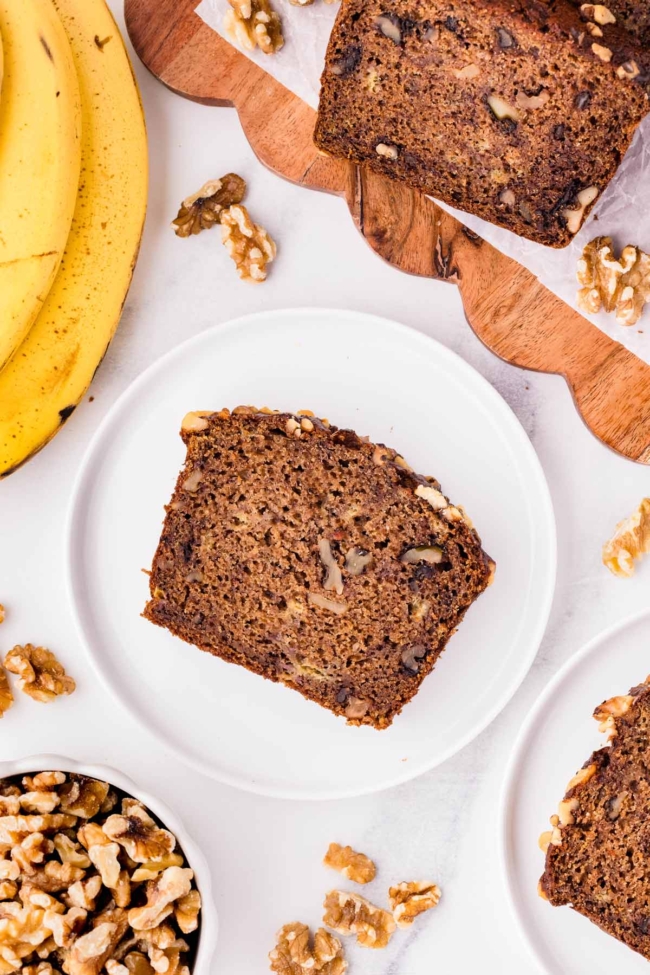 Slice of whole wheat banana nut bread on a white plate