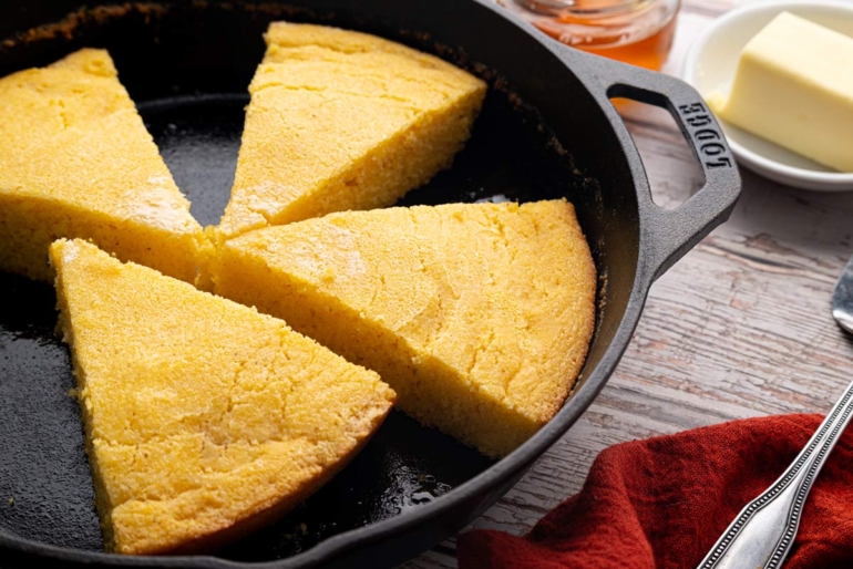 Homemade sourdough cornbread sliced into thick wedges in a cast iron skillet