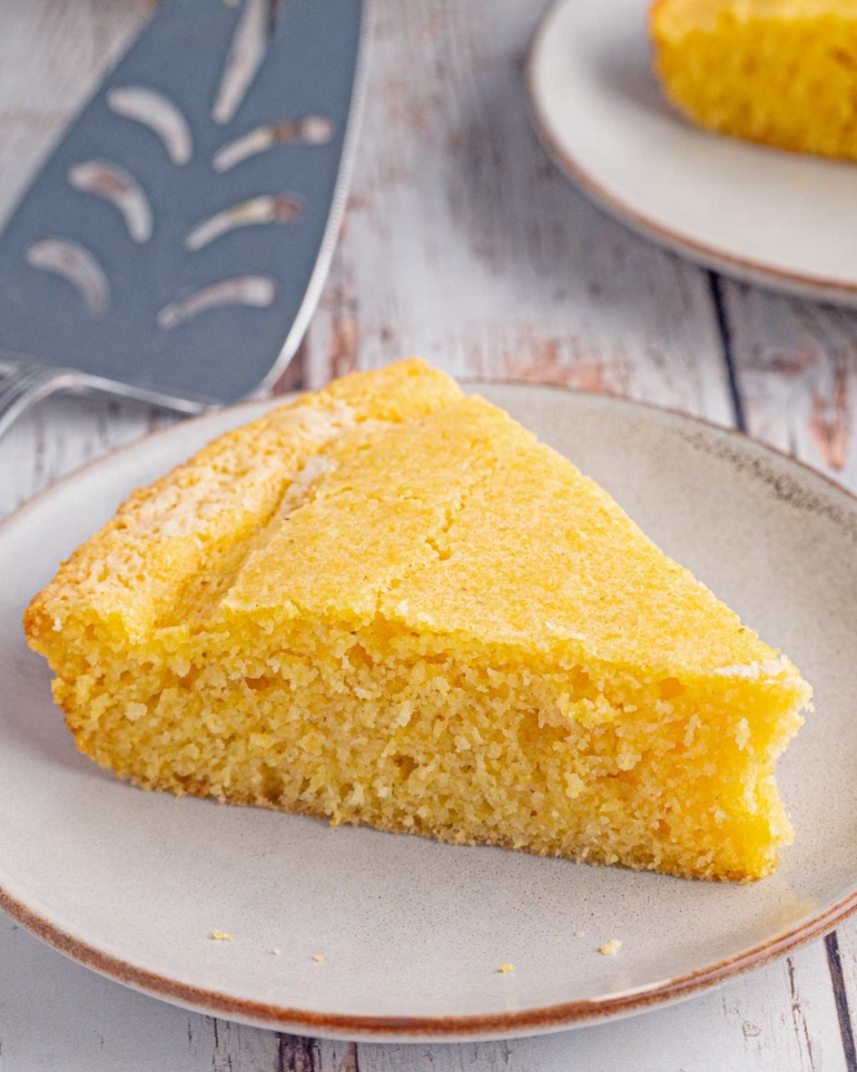 Close-up of a thick slice of sourdough cornbread showing its golden crust and tender crumb