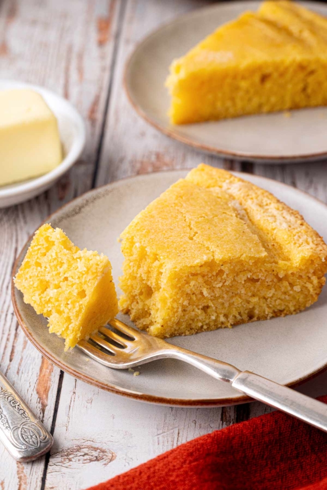 Slice of sourdough cornbread on a plate with a fork and butter